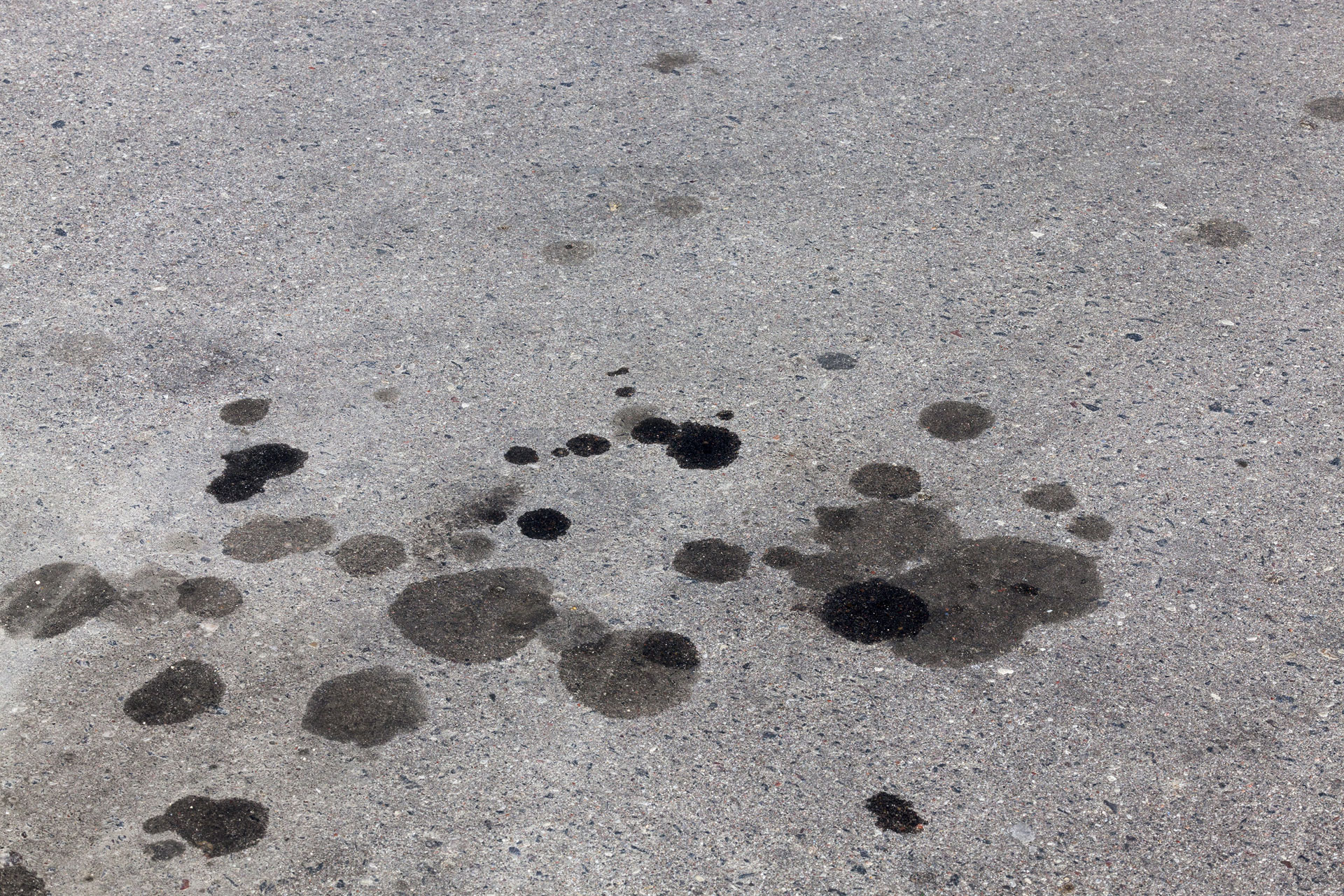 A concrete floor with multiple ugly oil stains.