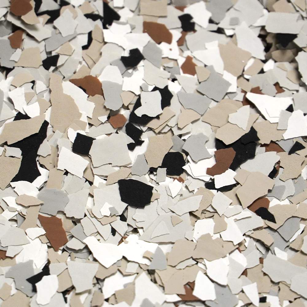 A collection of fragmented confetti pieces in neutral colors including white, black, and various shades of brown, creating a random, textured surface.