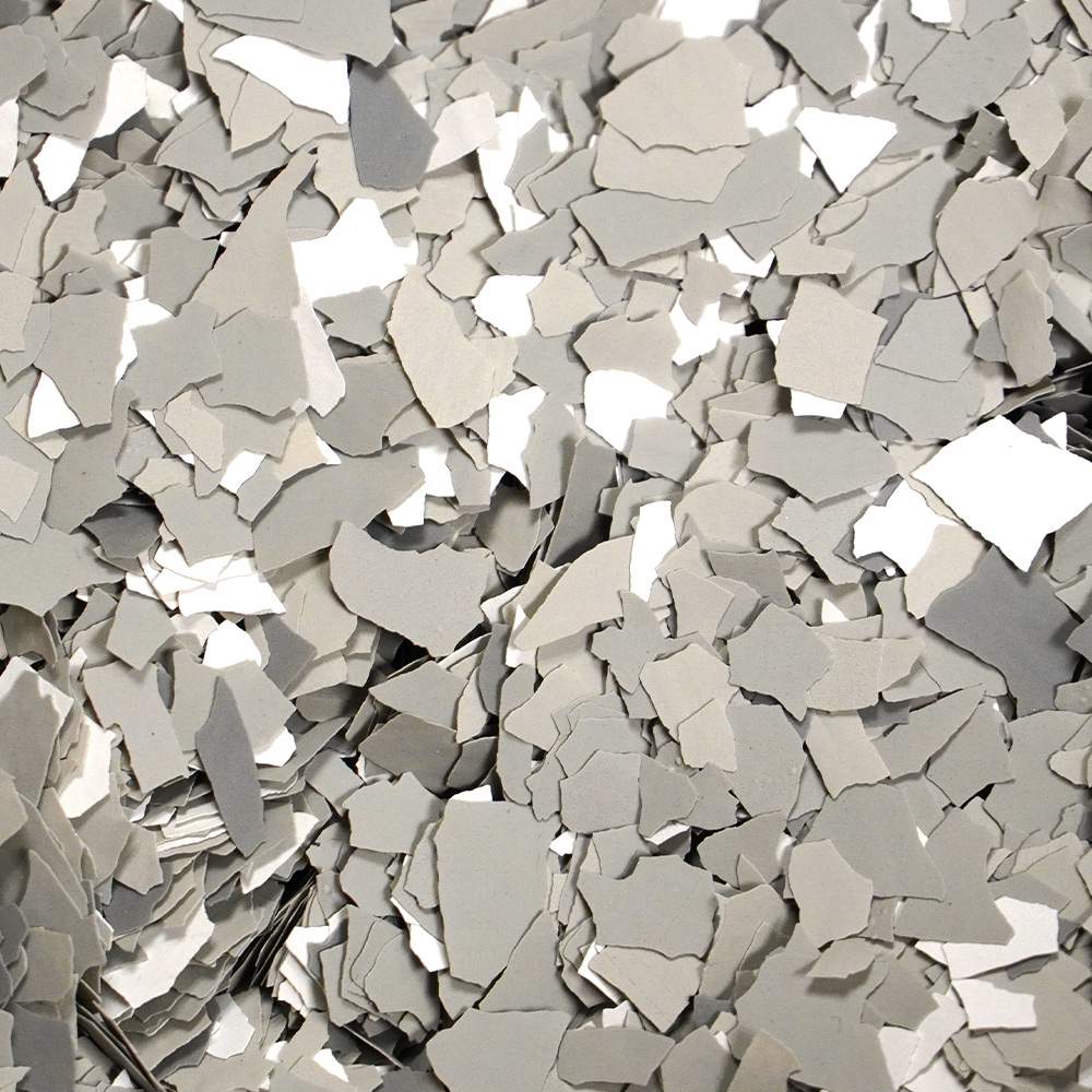A collection of grey confetti pieces scattered and overlapping, creating a textured appearance with various shades of grey.