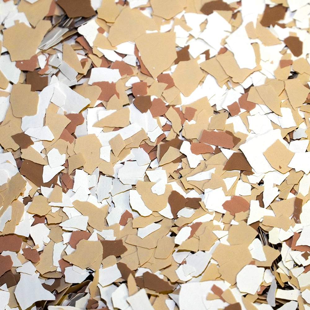 A dense layer of fragmented confetti pieces in varying shades of white and beige with a few black pieces interspersed, forming a textured surface.
